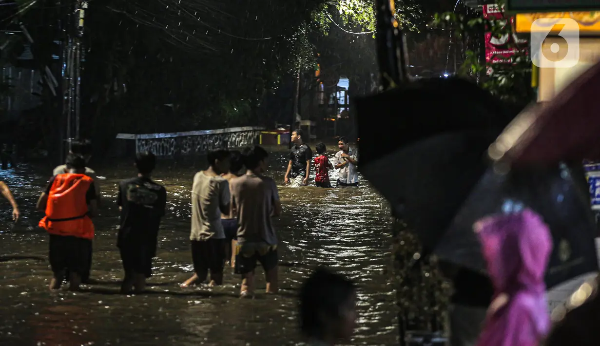 Sejumlah warga melintasi genangan banjir di kawasan Kemang, Jakarta, Selasa (4/10/2022). Jalan Kemang Utara IX tak bisa dilalui oleh kendaraan. Banjir menggenangi kawasan Pasar Kambing dan sejumlah rumah penduduk. (Liputan6.com/Faizal Fanani)
