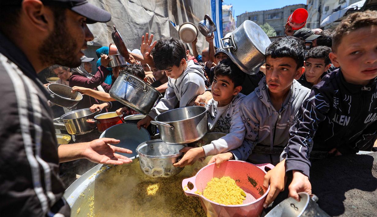 Orang-orang berebut untuk mendapatkan makanan hangat di kamp pengungsi Palestina, Nuseirat, Jalur Gaza Tengah pada Kamis 7 Mei 2026. Krisis kemanusiaan di Gaza per Mei 2026 mencapai titik kritis. (Eyad Baba/AFP)