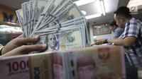 Teller menunjukkan uang dolar dan rupiah di penukaran uang di Jakarta, Junat (23/11). Nilai tukar dolar AS terpantau terus melemah terhadap rupiah hingga ke level Rp 14.504. (Liputan6.com/Angga Yuniar)