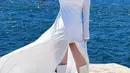Karina aespa melakukan photoshoot di atas kapal dengan mengenakan outfit serba putih. Karina mengenakan dress lengan panjang yang super panjang menjuntai dengan high slit di bagian depan, dipadukan high boots yang juga berwarna putih. [Foto: Instagram/katarinabluu]