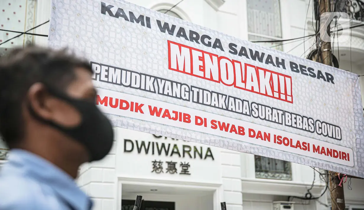 Seorang pria melintas di dekat spanduk peringatan untuk pemudik di kawasan Kartini, Sawah Besar, Jakarta, Senin (17/5/2021). Spanduk tersebut untuk memperingati warga yang kembali dari mudik lebaran agar membawa surat bebas COVID-19. (Liputan6.com/Faizal Fanani)
