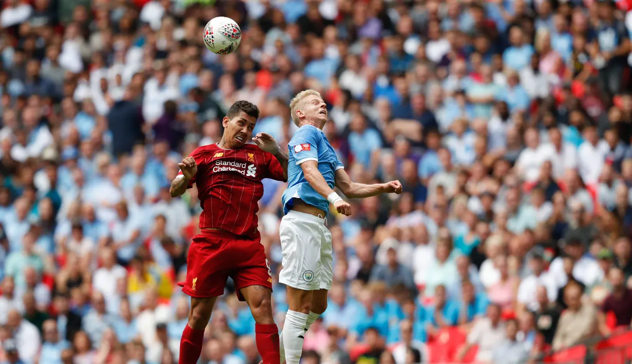 Gelandang Manchester City, Oleksandr Zinchenko, duel udara dengan gelandang Liverpool, Roberto Firmino, pada laga Community Shield di Stadion Wembley, London, Minggu (4/8). City menang 1-1 (5-4) atas Liverpool. (AFP/Adrian Dennis)