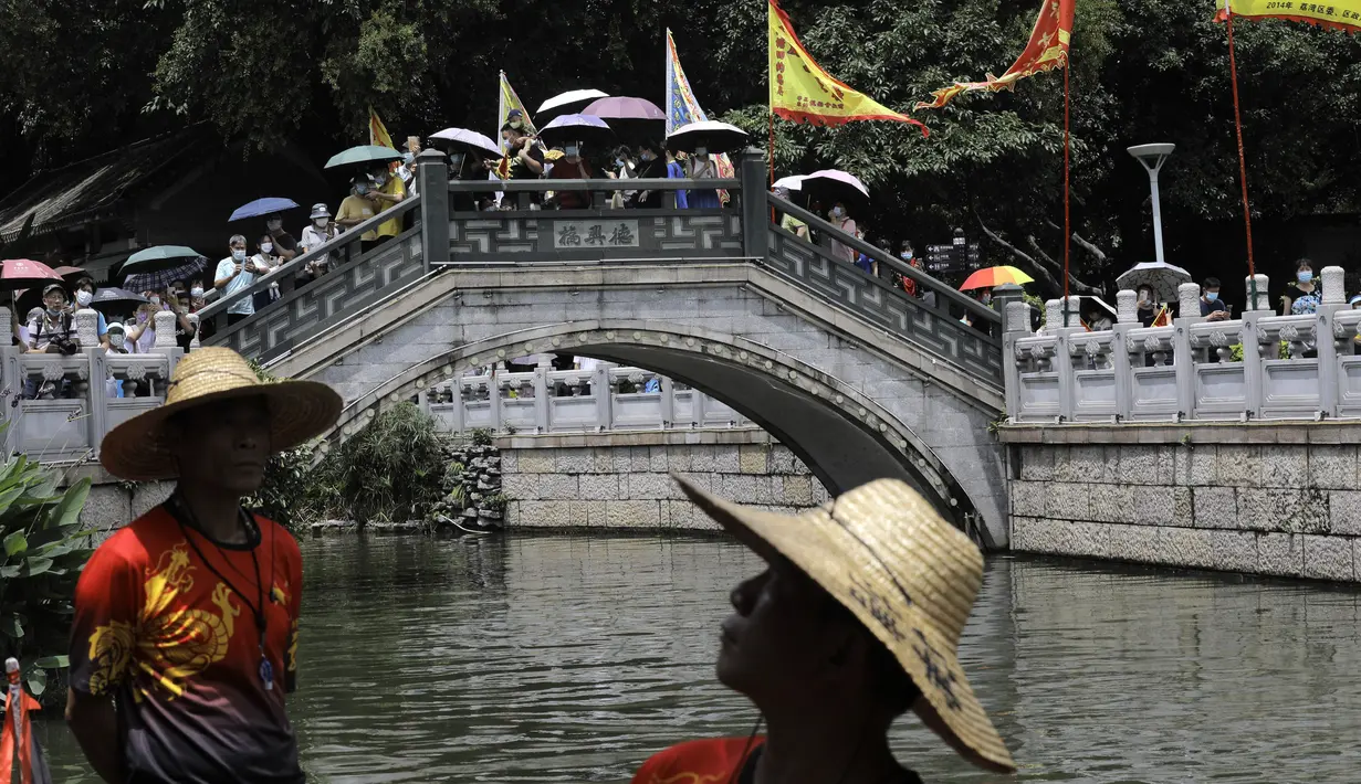 Warga berkerumun di jembatan untuk menunggu perahu naga di sepanjang kanal di kawasan bersejarah Teluk Lychee di Guangzhou di Provinsi Guangdong, China selatan, Jumat, 3 Juni 2022. Perlombaan perahu naga kembali digelar di beberapa bagian China untuk pertama kalinya sejak merebaknya pandemi pada akhir 2019, saat pembatasan dicabut bersama dengan penurunan besar  kasus COVID-19. (AP Photo/Caroline Chen)