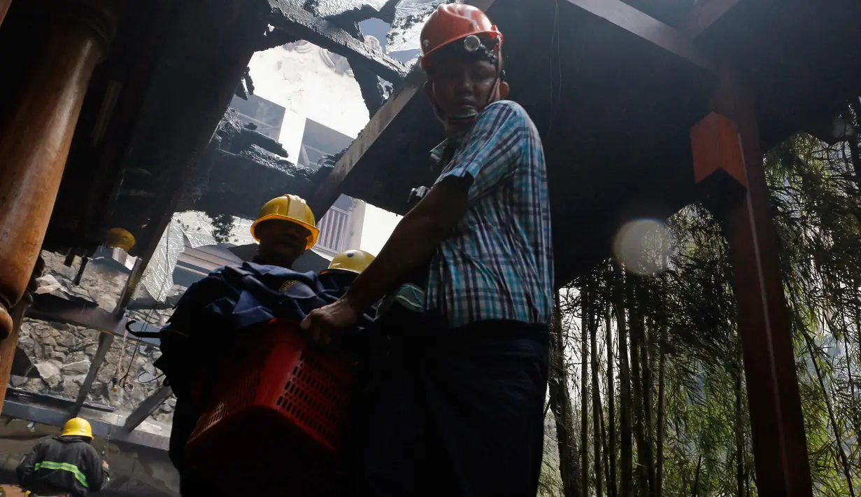 Dua pria membawa barang-barang saat kebakaran di Hotel Istana Kandawgyi di Yangon, Myanmar (19/10). Api telah melahap hotel bintang lima yang sering dikunjungi wisatawan asing di kota Yangon, Myanmar. (AP Photo/Thein Zaw)