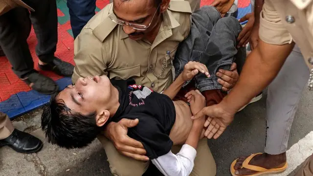 Polisi membantu korban penyerbuan saat ia kesulitan bernapas di dekat stadion di Bengaluru pada 4 Juni 2025. (AFP)