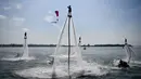 Seorang flyboarder (tengah) memberi hormat saat gladi bersih sehari jelang upacara pembukaan latihan angkatan laut multilateral Komodo 2025 di pelabuhan Benoa, Denpasar, Bali, pada 15 Februari 2025. (SONNY TUMBELAKA/AFP)