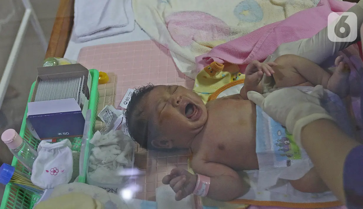 Seorang bayi menangis saat dikenakan popok oleh perawat dalam kegiatan pelatihan di RSIA Tambak, Jakarta, Kamis (18/02/2021). Melatih para ibu baru untuk memandikan bayi pertama tersebut dilakukan dengan menerapkan protokol kesehatan ketat. (Liputan6.com/Herman Zakharia)