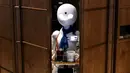 Robot humanoid mengantarkan minuman kepada pelanggan di Dawn Cafe, Tokyo, Jepang, 17 Agustus 2021. Peluncuran kafe ini bersamaan dengan Paralimpiade yang akan dibuka pada 24 Agustus. (Behrouz MEHRI/AFP)