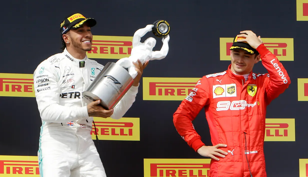 Pebalap Mercedes Lewis Hamilton (kiri) memegang trofi juara disaksikan pebalap Ferrari Charles Leclerc setelah menjuarai F1 GP Prancis 2019 di Sirkuit Paul Ricard, Minggu (23/6/2019). Hamilton tampil dominan dan menjadi juara F1 GP Prancis 2019. (AP Photo/Claude Paris)