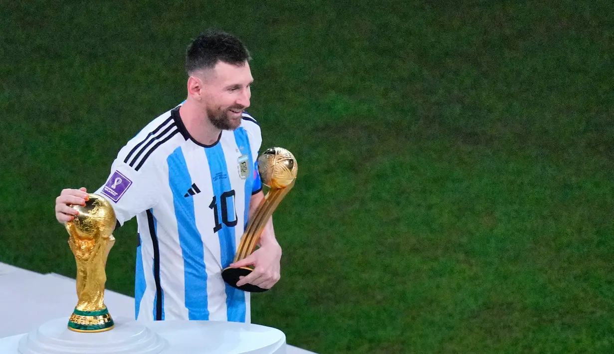 Pemain ArgentinaLionel Messi memegang trofi penghargaan Bola Emas saat membelai trofi Piala Dunia 2022 usai melawan Prancis pada pertandingan sepak bola final Piala Dunia 2022 di Stadion Lusail, Lusail, Qatar, 18 Desember, 2022. Lionel Messi dinobatkan sebagai peraih Bola Emas atau Golden Ball sebagai perlambang pemain terbaik selama Piala Dunia 2022 setelah memimpin Argentina menaklukkan Prancis dalam babak final. (AP Photo/Hassan Ammar)