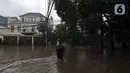 Warga melintasi banjir di Jalan Hang Lekir, Kebayoran Lama, Jakarta Selatan, Rabu (1/1/2020). Banjir tersebut disebabkan karena tingginya intensitas hujan yang mengguyur sejak Selasa (31/12/2019). (Liputan6.com/Johan Tallo)