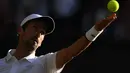 Petenis Serbia, Novak Djokovic bersiap melakukan servis ke petenis AS, Denis Kudla pada babak kedua Wimbledon di All England Lawn Tennis Club, London, Kamis (4/7/2019) dini hari. Petenis nomor satu dunia itu menang straight set 6-3, 6-2, 6-2 atas Denis Kudla. (Ben STANSALL/AFP)
