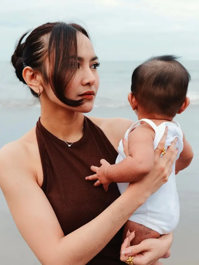 Gaya Mahalini saat menggendong anak di pinggir pantai.  [@mahaliniraharja]