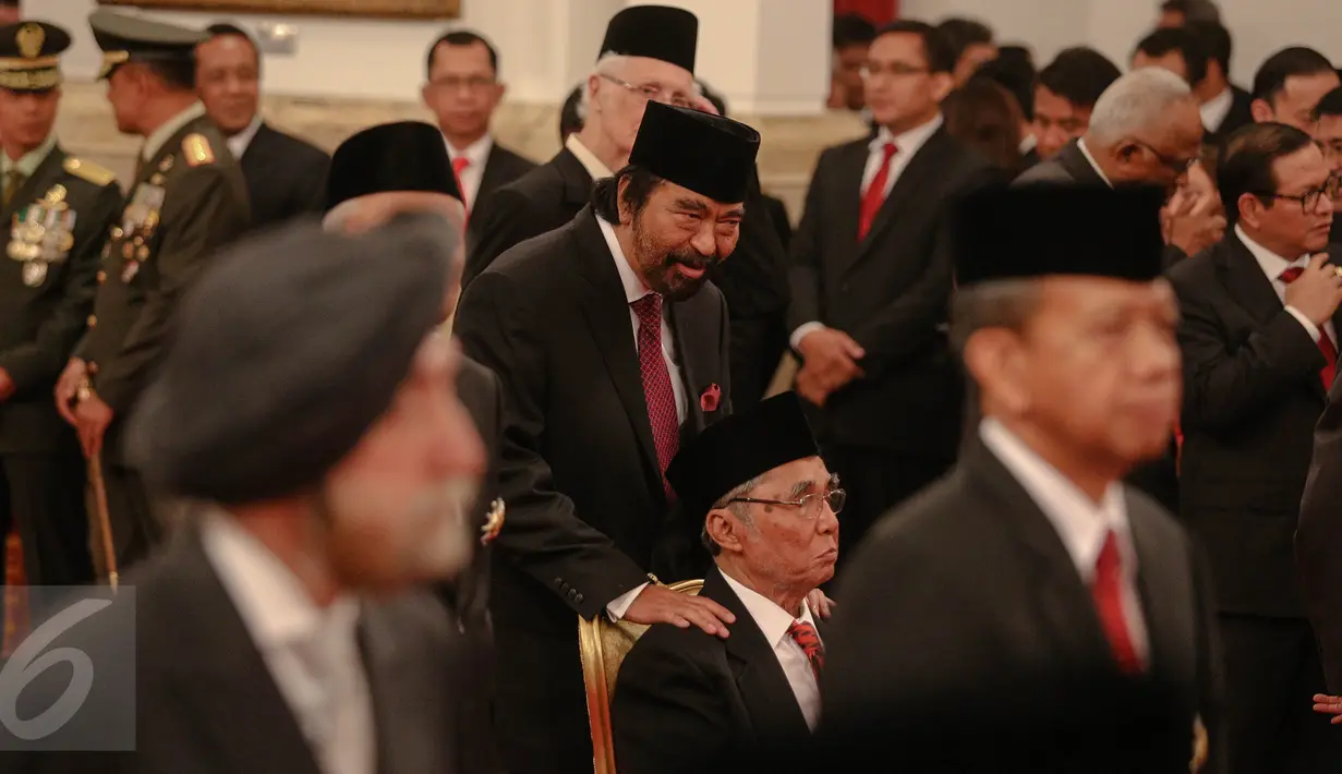 Tokoh Pers Nasional, Surya Paloh memegang pundak anggota DPR RI Fraksi PDI-P, Sabam Sirait saat acara pemberian tanda kehormatan oleh Presiden Jokowi kepada tokoh nasional di Istana Negara, Jakarta, Kamis (13/8). (Liputan6.com/Faizal Fanani)