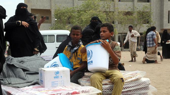 Dua bocah menerima bantuan yang diberikan oleh Komisaris Tinggi PBB untuk Pengungsi (UNHCR) di kota Hodeidah, Yaman (11/4). Perang di Yaman telah menewaskan lebih dari 10 ribu orang dan membuat lebih dari dua juta orang mengungsi. (AFP Photo/Abdo Hyder)