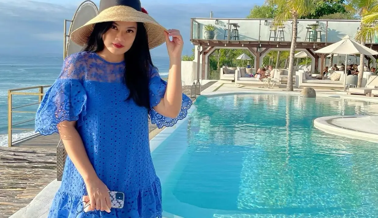 Dress renda warna biru dipadukan dengan boater hat tampak sempurna dikenakan Titi. [Foto: IG/titi_kamall].