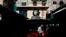 Warga beraktivitas di bawah sebuah mural pahlawan Revolusi Kuba Ernesto 'Che' Guevara yang menghadap ke pasar makanan di Havana, Kuba (28/12). Havana adalah kota terbesar di Kuba dan di seluruh Karibia. (AP Photo / Desmond Boylan)