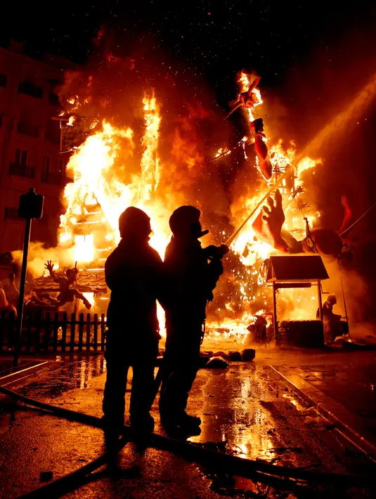 Pemadam kebakaran mengendalikan api pada malam terakhir festival tradisional Fallas di Valencia, Spanyol, Selasa (19/3).  Las Fallas adalah festival budaya yang diselenggarakan oleh warga Valencia pada 15 sampai 19 Maret setiap tahunnya. (AP/Alberto Saiz)