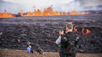 Orang-orang melihat aktivitas di gunung berapi Fagradalsfjall di Islandia pada Rabu (3/8/2022), yang terletak 32 kilometer (20 mil) barat daya ibu kota Reykjavik dan dekat dengan Bandara Internasional Keflavik. Video menunjukkan gunung berapi itu memuntahkan magma dari celah sempit sekitar 100 hingga 200 meter di atas bidang lava dari letusan tahun lalu. (AP Photo/Marco Di Marco)
