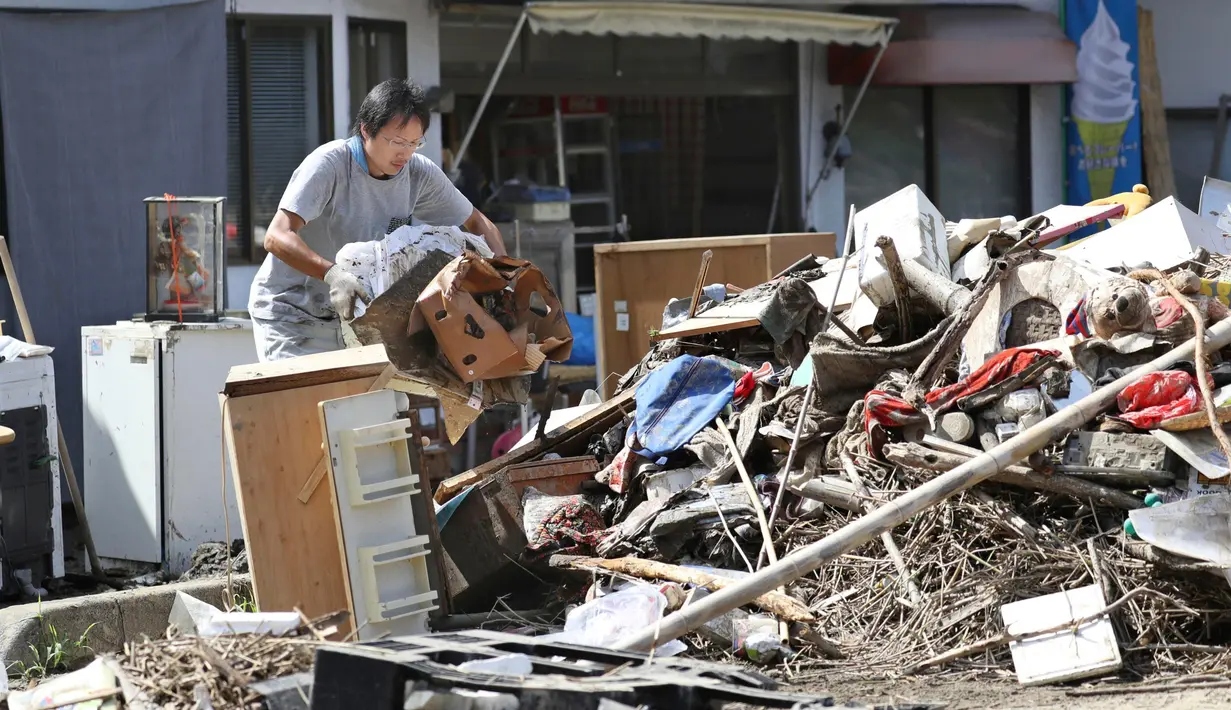 Warga membuang puing-puing usai banjir menerjang  Soja, Prefektur Okayama, Jepang, Senin (9/7). (Takaki Yajima/Kyodo News via AP)