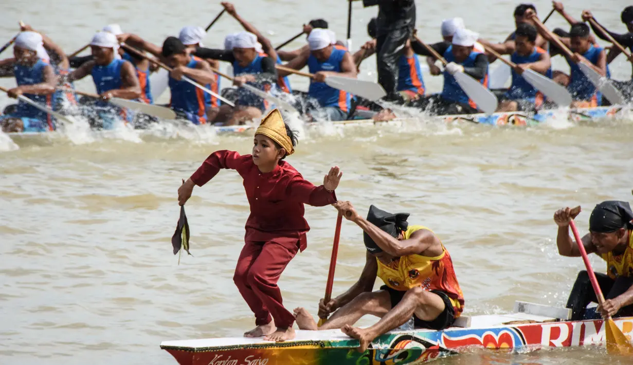 Seorang anak laki-laki menari di bagian depan perahu tradisional selama festival balap perahu Pacu Jalur di Sungai Kuantan, Kabupaten Kuantan Singingi, Provinsi Riau, pada 21 Agustus 2025. (Wahyudi/AFP)