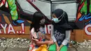 Anak-anak berbincang di depan mural bertema COVID-19 di kawasan Tanah Tinggi, Tangerang, Banten, Rabu (20/1/2020). Kegiatan ini dalam rangka mensosialisasikan bahaya penyebaran COVID-19 kepada warga pengguna jalan umum. (merdeka.com/Arie Basuki)