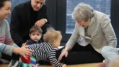Perdana Menteri Inggris Theresa May bermain dengan bayi saat berkunjung ke pusat kesehatan di London, Inggris, Kamis (22/11). Theresa menjabat sebagai Perdana Menteri Inggris sejak 2016. (Andrew Matthews/Pool via AP)