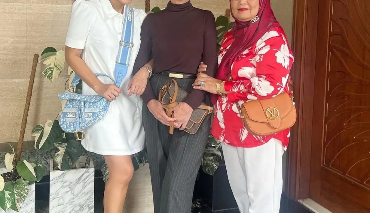 Berfoto bersama ibu kandung dan mama mertua, Titi Kamal terlihat berusia 20an. Ia kenakan shirt dress putih berlengan puff dan sling bag Dior [@titi_kamall]