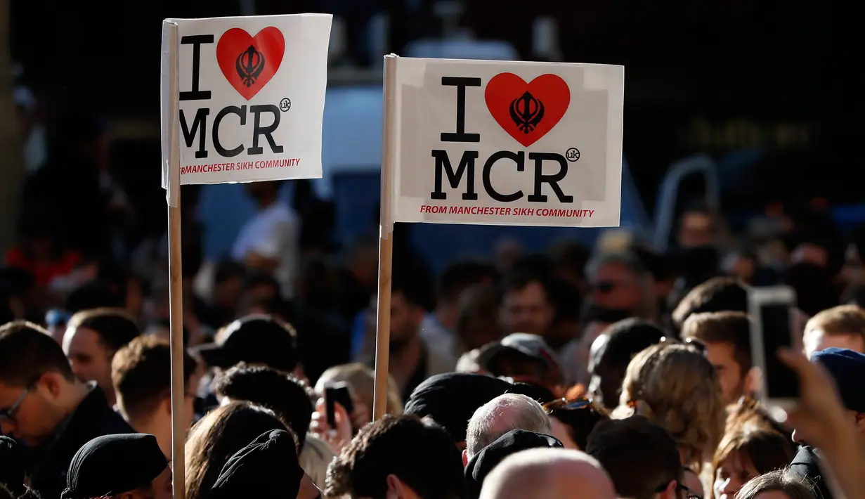 Sejumlah orang membawa poster 'I Love MCR' di pusat kota Manchester, sehari setelah ledakan bom saat konser Ariana Grande, Selasa (23/5). Mereka menggelar doa bersama untuk korban serangan bom yang menewaskan 22 orang (AP Photo/Kirsty Wigglesworth)