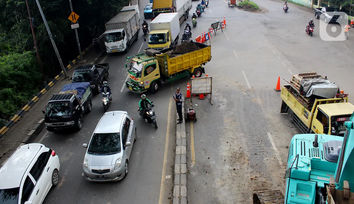 Petugas Dishub mengatur lalu lintas saat sistem rekayasa lalu lintas one way atau satu arah di ruas Jalan Daan Mogot arah Tangerang Kota, Senin (13/1/2020). Penerapan ini dilakukan karena kemacetan akibat perbaikan jalan ambles di kawasan Daan Mogot. (merdeka.com/Magang/Muhammad Fayyadh)