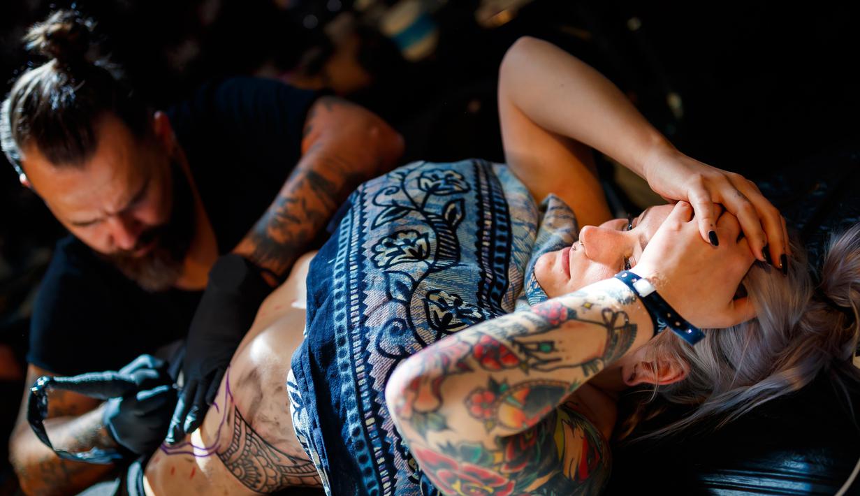 Seorang seniman mentato badan pengunjung wanita dalam acara edisi keempat Montreux Tattoo Convention di Montreux, Swiss  (22/9). Montreux Tattoo Convention berlangsung selama tiga hari. (Valentin Flauraud/Keystone via AP)