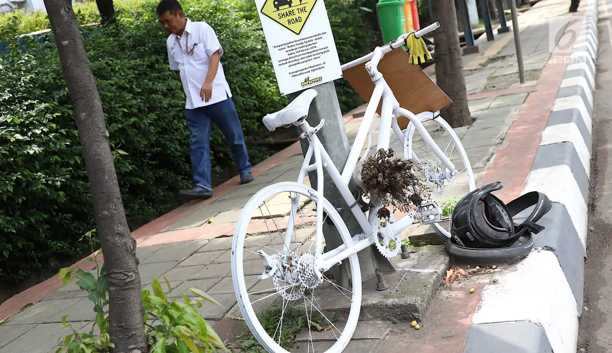 Pejalan kaki melintasi monumen sepeda putih atau ghost bike di sebuah tiang kawasan Jenderal Gatot Subroto, Jakarta, Senin (12/3). Monumen itu untuk mengenang pesepeda Raden Sandy Syafiek yang tewas tertabrak mobil. (Liputan6.com/Immanuel Antonius)