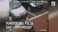 Seorang pengendara motor sempat-sempatnya membeli pulsa saat lampu merah.