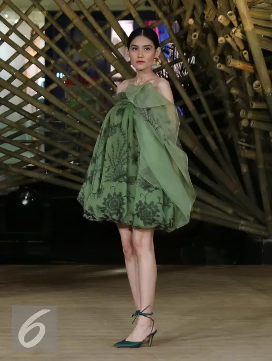 Model membawakan busana rancangan Edward Hutabarat dalam 'Kenduri' di Senayan City, Jakarta, Senin (15/8). Edward berkolaborasi dengan Joko Avianto, untuk membuat sebuah rumah bambu sebagai latar belakang peragaan malam itu. (Liputan6.com/Herman Zakharia)