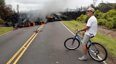 Seorang warga berfoto dengan latar belakang lava pijar erupsi Gunung Kilauea yang menutupi jalan di Pahoa, Hawaii, Amerika Serikat, Sabtu (5/5). Menurut warga, aliran lava tersebar di area seluas 200 yard atau 182 meter persegi. (AP Photo/Marco Garcia)