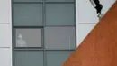 Pria bermasker berdiri dekat jendela sebuah blok akomodasi staf di mana warga negara Inggris yang diterbangkan dari China dan berisiko terinfeksi virus corona sedang dikarantina di RS Arrowe Park, Wirral, Liverpool, Rabu (5/2/2020). (AP Photo/Jon Super)