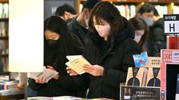 Orang-orang yang memakai masker membaca buku di toko buku di Seoul, setelah Korea Selatan mencabut mandat masker dalam ruangan saat kasus COVID-19 yang terus menurun, Senin (30/1/2023). Mulai Senin, orang dapat mengunjungi sebagian besar tempat tanpa masker  karena pemerintah mencabut mandat penggunaan masker dalam ruangan yang telah diberlakukan sejak Oktober 2020. (Jung Yeon-je / AFP)