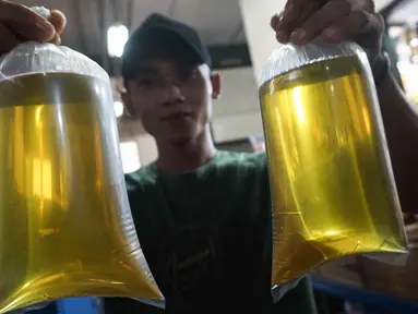 Pedagang menunjukkan plastik berisi minyak goreng curah di Pasar Senen, Jakarta, Selasa (31/5/2022). Kementerian Perindustrian mencabut subsidi minyak goreng curah kepada pelaku usaha mulai Selasa (31/5/2022). (Liputan6.com/Herman Zakharia)