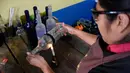 Salah satu proses jelang pemotongan botol di Guatemala (12/2). Dengan peralatan sederhana, mereka menyulap botol-botol tersebut menjadi gelas dan vas yang laris dijual di supermarket. (AFP PHOTO/JOHAN Ordonez)