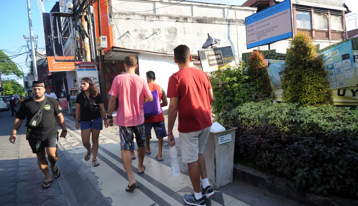 <p>Turis mancanegara berjalan melewati papan izin mendirikan bangunan (biru) di bekas lokasi bom Bali Sari Club di Kuta, Bali, Jumat (26/4). Perdana Menteri Morrison kesal karena saat terjadi serangan Bom Bali pada 2002 di Sari Club, puluhan warga Australia tewas di tempat ini. (SONNY TUMBELAKA/AFP)</p>
