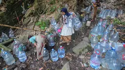 Warga berjalan untuk mengambil air untuk minum dan kebutuhan mck rumah  di sumber mata air Sumur Bendung, Gunung Batur, Kota Cilegon, Banten, Minggu, (15/7/2026). (KLY/Arie Basuki)