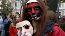 Seorang perempuan berpose dengan dandanan menyerupai zombie ketika berpartisipasi dalam 'Zombie Walk' di pusat Kota Kiev, Ukraina, 26 Oktober 2019. Menjelang perayaan Halloween pada 31 Oktober mendatang, warga di beberapa belahan dunia sudah mulai melakukan acara bertema horor. (AP/Efrem Lukatsky)