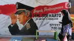 Seorang warga melintasi mural di Kampung Budaya Kawasan Jakarta Barat, Selasa (19/11/2019). Pemprov Jakarta Barat melakukan penataan kawasan pemukiman di beberapa lokasi, salah satunya di Jalan Katalia I Timur. (Liputan6.com/Herman Zakharia)