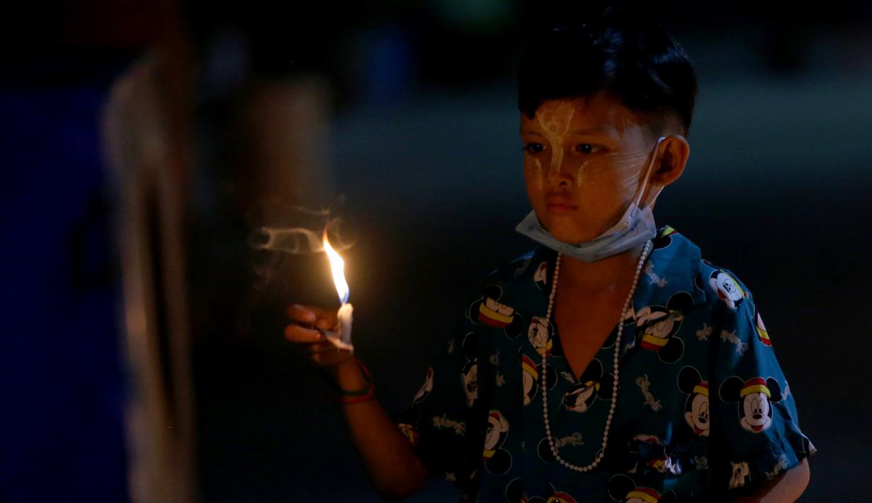 Seorang anak menyalakan lilin saat Festival Tazaungdaing di Yangon, Myanmar (29/11/2020). Festival itu dirayakan di Myanmar sebagai hari libur nasional dan menandai akhir musim hujan. (Xinhua/U Aung)