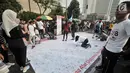 Pengunjung membubuhkan tanda tangan di atas spanduk raksasa saat car free day (CFD) di Bundaran HI, Jakarta, Minggu (22/7). Aksi ini sebagai motivasi agar atlet Indonesia menjadi juara di Asian Games 2018. (Merdeka.com/Iqbal Nugroho)