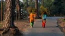 Wanita desa berjalan di antara pohon-pohon pinus membawa rumput untuk hewan peliharaan mereka di Dharamsala, India, Minggu (14/10). Sekitar 800 juta warga India hidup dalam kemiskinan. (AP Photo/Ashwani Bhatia)