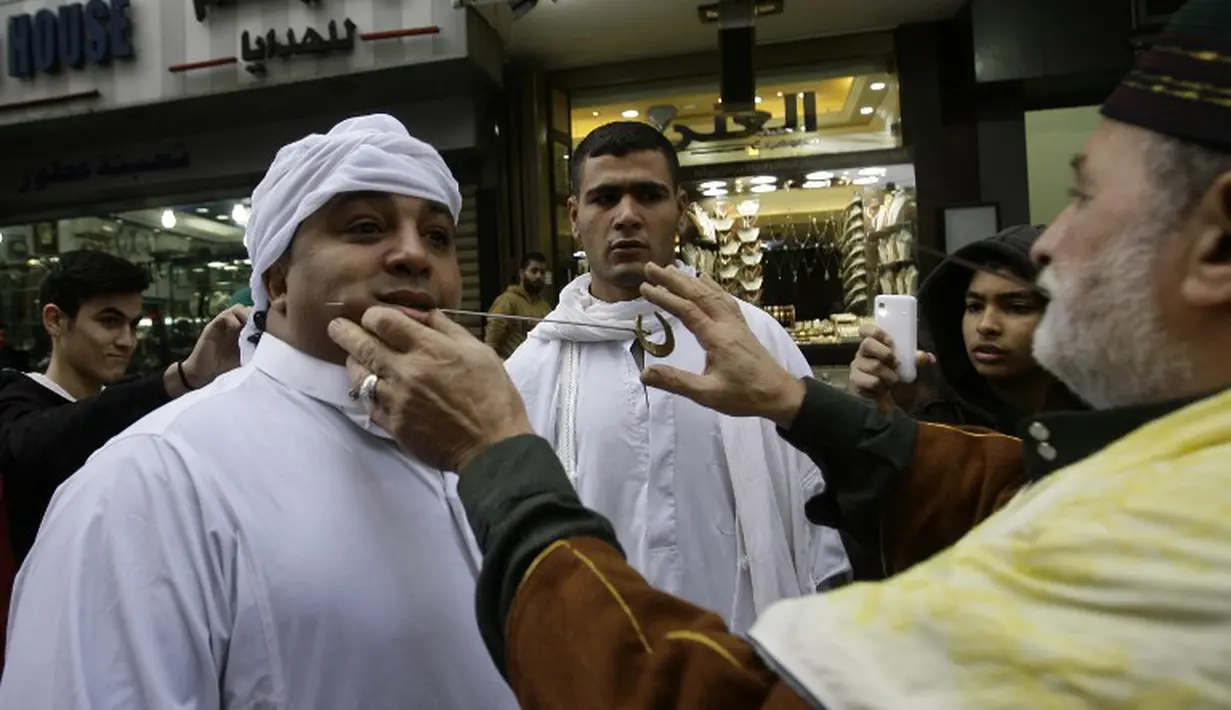 Seorang pria di Lebanon ditusuk pipinya dengan jarum panjang saat memperingati kelahiran Nabi Muhammad, Lebanon, Sabtu (3/1/2015). (AFP Photo/Mahmud Zayyat)