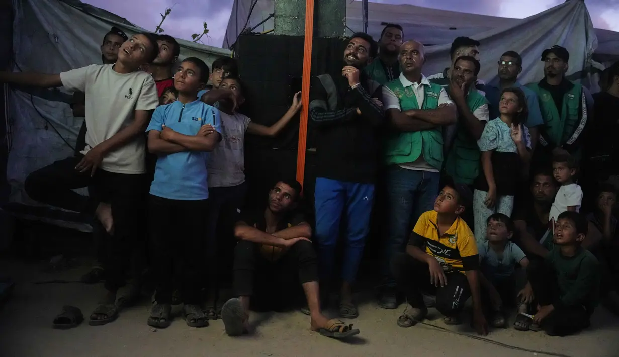 Warga Palestina menyaksikan siaran langsung pertandingan sepak bola Piala Dunia antara Spanyol dan Arab Saudi melalui layer lebar di Nuseirat, Jalur Gaza Tengah, Minggu 21 Juni 2026. (AP Photo/Abdel Kareem Hana)