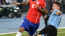 Gelandang Chile, Arturo Vidal (kiri) berusaha melewati gelandang Cristian Rodriguez di perempat final Copa Amerika 2015 di National Stadium, Santiago, Chile, (25/6/2015). Chile melaju ke semifinal usai mengalahkan Uruguay 1-0. (REUTERS/Henry Romero)