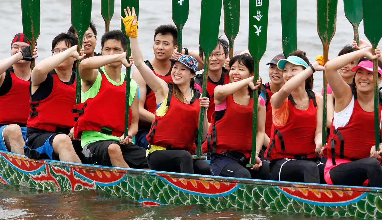 Seorang peserta melambaikan tangan saat mengikuti perlombaan tradisional China, Dragon Boat di Taipei, taiwan, Minggu (28/5). Perlombaan perahu naga ini untuk mengenang kematian penyair Qu Yuan yang tewas tenggelam pada 278 SM. (AP Photo/Chiang Ying-ying)
